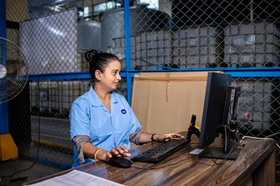 A female factory worker using a computer in an industrial environment.
