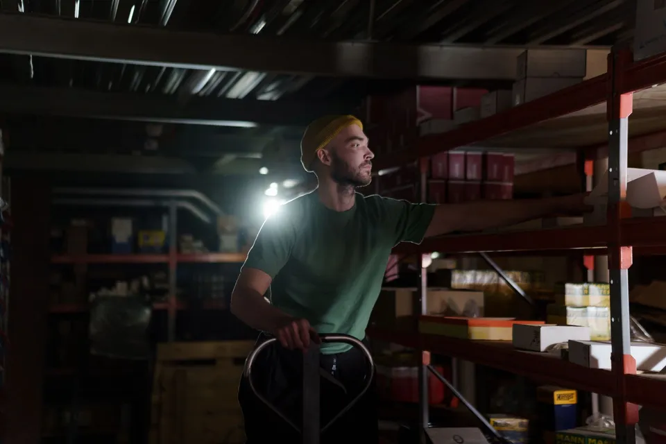 A dedicated worker organizing inventory on warehouse shelves with focused concentration.
